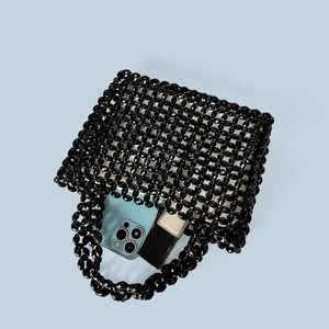 Detail of black acrylic beaded bag showing open mesh weave with phone and lipstick inside
