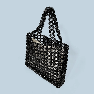 Macro view showing the black acrylic beaded texture and fabric lining of the tote bag