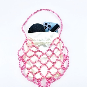 Detail view of a pink beaded handbag with a white satin drawstring inner lining pouch