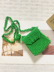 Gros plan d'un mini sac vert fait main en perles avec rabat carré et texture tissée