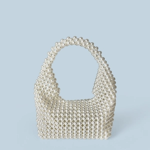 Detail of handcrafted white faux pearl woven handbag showing texture and beadwork