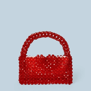 Détail de la texture perlée rouge et de la boucle en cœur de ce sac à main en acrylique