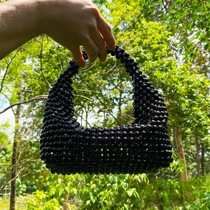 Detailed view of a handmade black beaded boston bag with an integrated woven handle