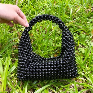 Detail of a handmade black beaded Boston handbag with a woven pearl texture handle