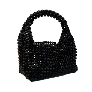 Detail of handcrafted black beaded handbag with high-gloss pearls and structured top handle
