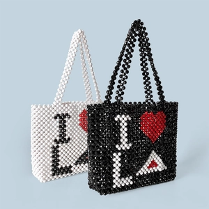 Detail of handmade beaded tote bags with heart and L letter patterns on blue background