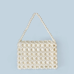 Detailed view of handmade faux pearl beaded handbag with mesh pattern on blue background