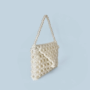 Detailed view of handcrafted faux pearl beaded handbag with unique woven saddle shape design