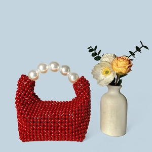 Détail du sac rouge perlé avec une élégante poignée en grosses perles blanches