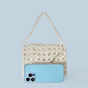 Detailed close-up of white handmade beaded pearl handbag showing texture and size with a phone