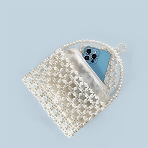 Detail of handmade pearl beaded mini bag showing capacity with a blue smartphone inside