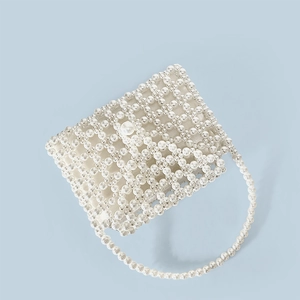 Detail shot of the handcrafted faux pearl woven pattern on a chic beaded handbag