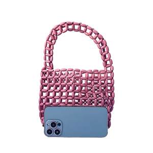 Pink beaded handmade handbag shown with a smartphone for scale and size comparison