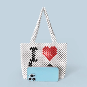 Handmade beaded handbag with I Love heart pattern shown next to a phone for size scale