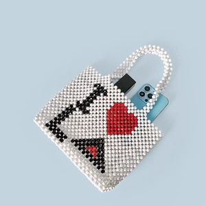 Detail of handmade beaded tote bag with heart pattern showing interior space for a smartphone