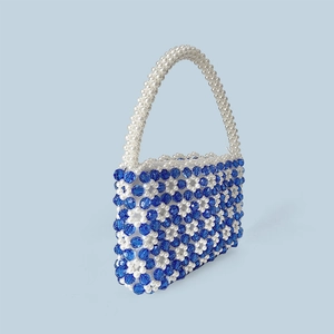Detail einer handgefertigten Perlenhandtasche mit blauem Blumenmuster und Perlenakzenten