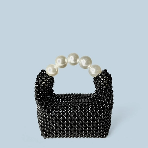 Détail du mini sac tressé en perles noires avec une anse de perles blanches
