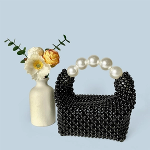 Détail d'un sac à main perlé noir fait main avec de grandes poignées en perles blanches