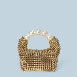 Détail d'un sac à main en perles dorées avec une poignée en grosses perles blanches