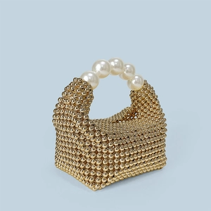 Détails d'un sac à main tressé doré avec une anse élégante en perles blanches