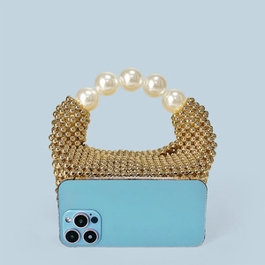 Mini sac à main perlé doré avec anse en perles montrant la taille avec un téléphone
