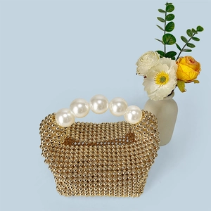 Détail du sac perlé doré tissé à la main avec d'élégantes poignées en perles blanches