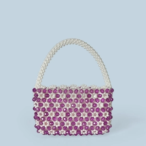 Nahaufnahme einer handgefertigten Perltasche mit violetten Kristallen und weißen Perlen