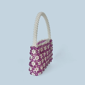 Detailaufnahme der handgefertigten Perlentasche mit violetten Blumen und weißen Perlen