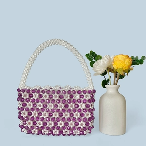 Detail der handgefertigten Perltasche mit lila-weißem Blumenmuster und PerlenGriff