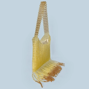 Detail of yellow beaded handbag featuring long gradient tassels and woven strap