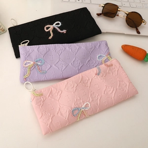 Bow tie pencil case with embossed diamond pattern in black, purple and pink colors