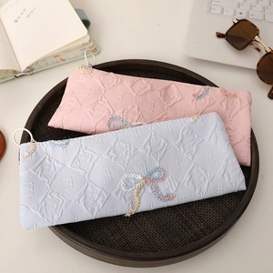 Pink and blue embossed bow pencil cases with large capacity in a cozy desk setting