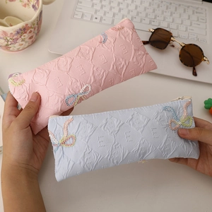 Detail of fabric pencil case with embossed E letter and embroidered colorful bow tie