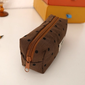 Detailed close-up of brown corduroy pencil case texture with black polka dots