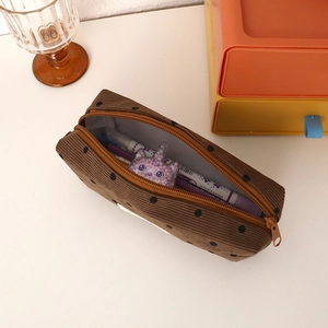 Close-up of brown polka dot corduroy pencil case with top zipper and soft texture