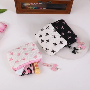 Detailed view of bow print quilted makeup pouch with pearl zipper pull and mini cosmetics