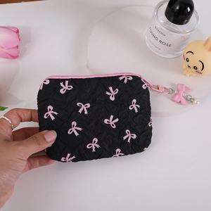 Detail of black quilted bow pouch featuring a pink ribbon zipper and pearl pendant