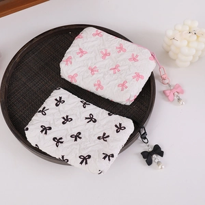 Detail of white quilted fabric mini pouches with pink and black bow prints and pearl charms
