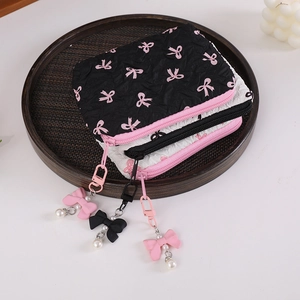 Close-up of bow print puckered fabric coin pouches with pearl zipper charms on wooden tray