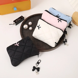 Quilted bow cosmetic bags in black, white, pink and blue set on a wooden tray