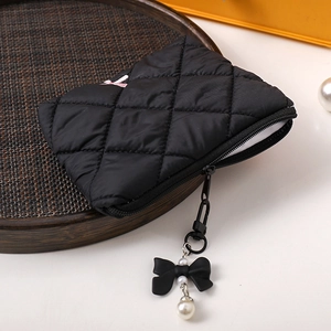 Detailed macro view of black quilted makeup bag with bow and pearl zipper charm