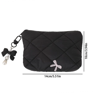 Detail view of black quilted makeup bag with silver bow embroidery and pearl charm