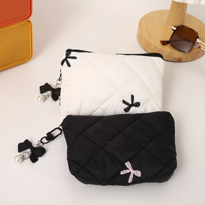 Close-up of quilted cosmetic bags in black and white with cute embroidered bows and pearls