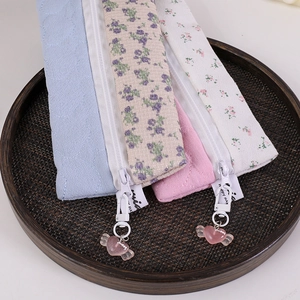 Close-up of floral quilted fabric pencil cases with heart pendants in a woven tray