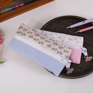 Detailed view of floral canvas pencil cases with heart pendants on a wooden tray