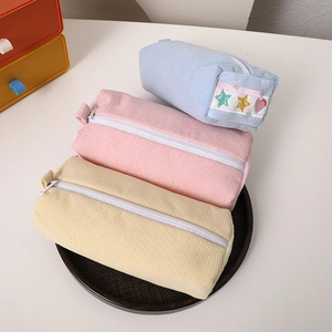Detailed close-up of quilted waffle fabric pencil cases in blue, pink, and beige tones