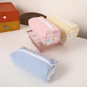 Close-up of waffle textured pencil cases in pink, yellow and blue with star patterns
