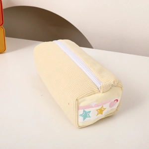 Close-up of light yellow corduroy pencil case with colorful star embroidery and white zipper