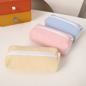 Detailed waffle texture fabric stationery pouches in cream, pink, and blue with zippers