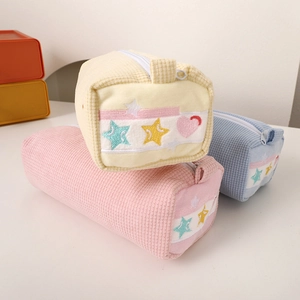 Close-up of pastel corduroy pencil cases with embroidered stars and hearts